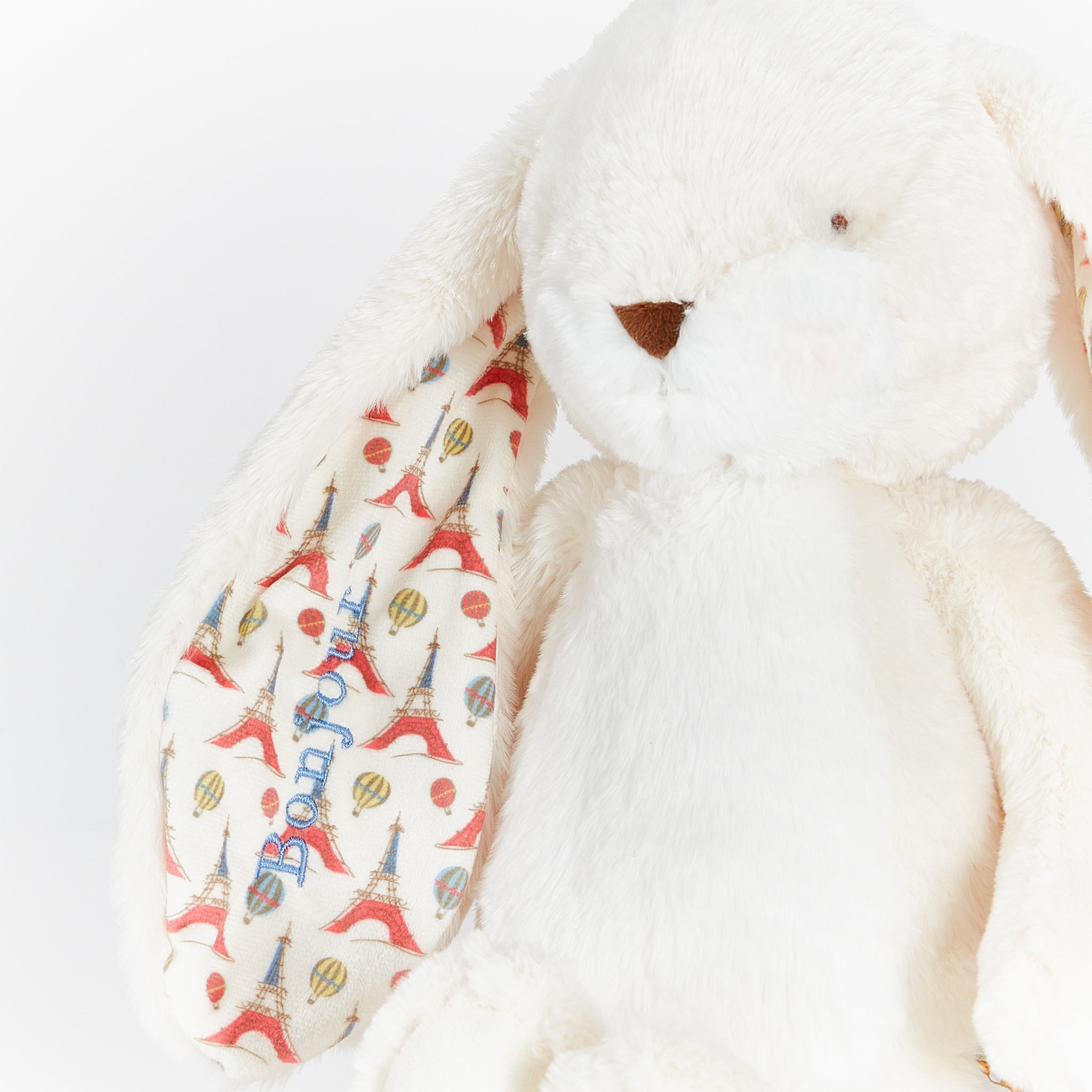 White plush bunny with colorful patterned ear on a white background