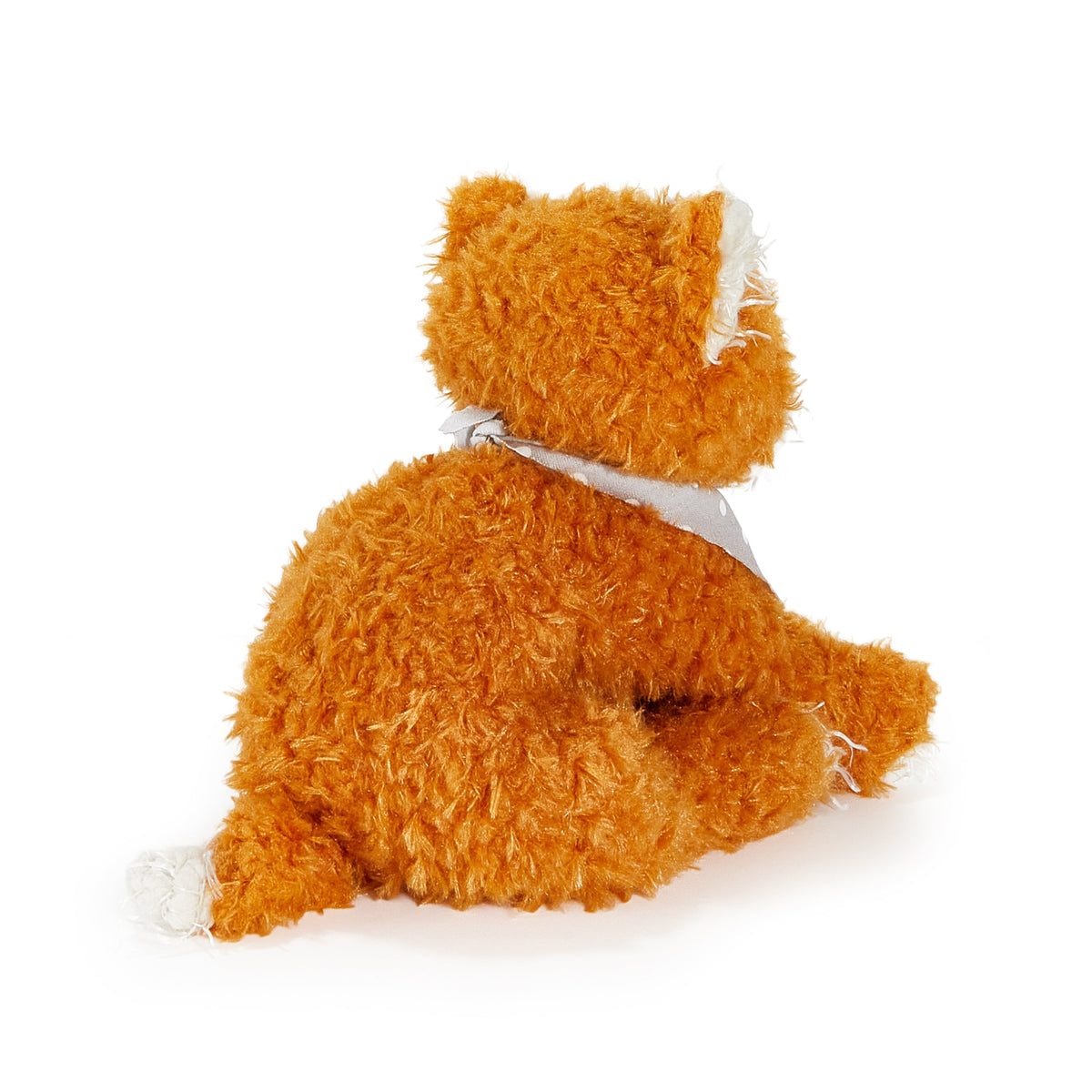 An orange fluffy stuffed cat plush toy sitting down, viewed from the back, wearing a light gray bandana around its neck, on a solid white background.