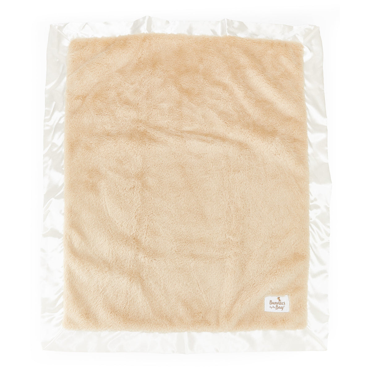 A square beige plush fleece blanket with a white satin border, sealed in a clear plastic vacuum bag. A small white brand label for 'Bunnies By The Bay' is visible in the bottom right corner.