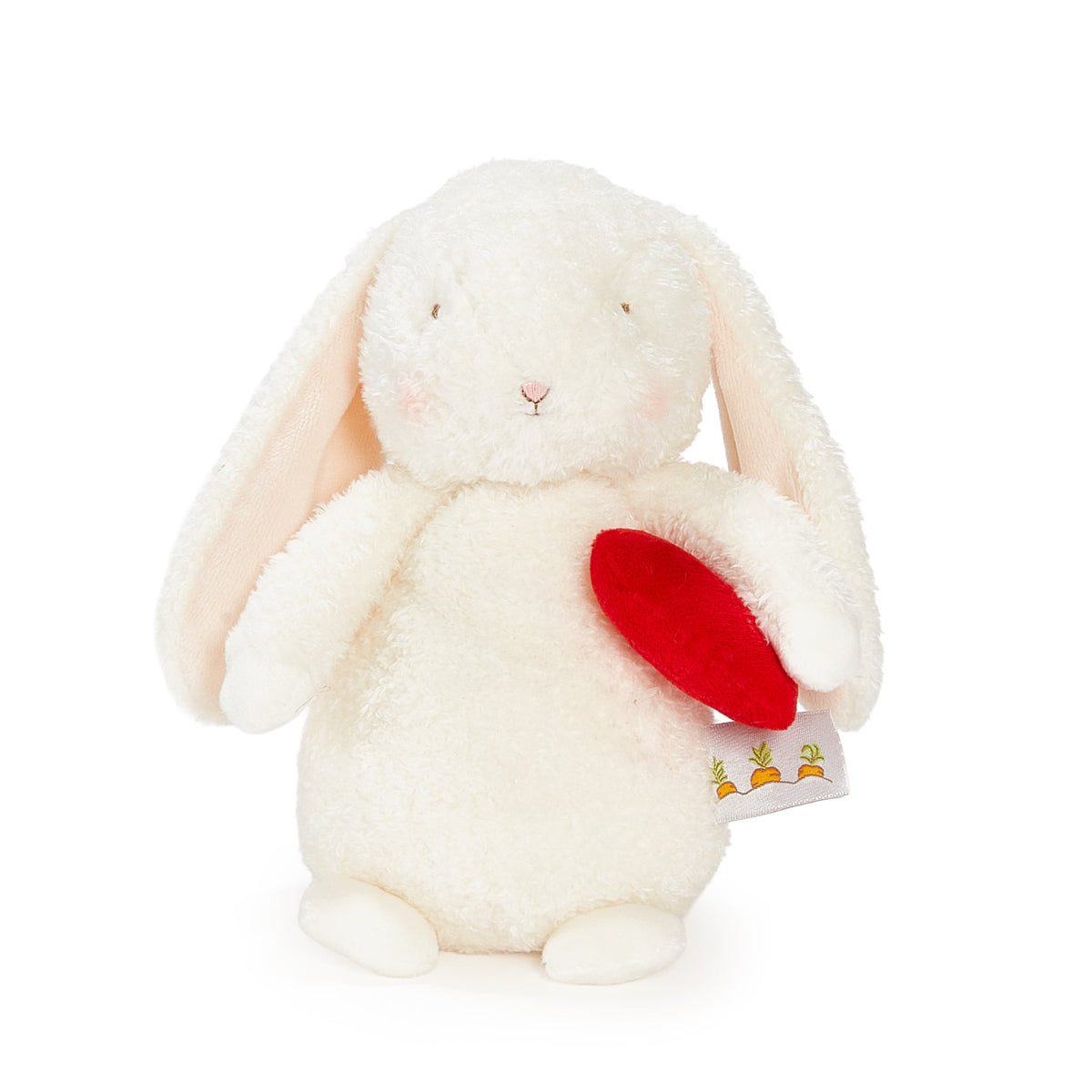 A plush white bunny toy with long floppy ears, a small pink stitched nose, and a red heart-shaped accessory held in its front paws. A small fabric tag with carrot illustrations is attached near the right side.