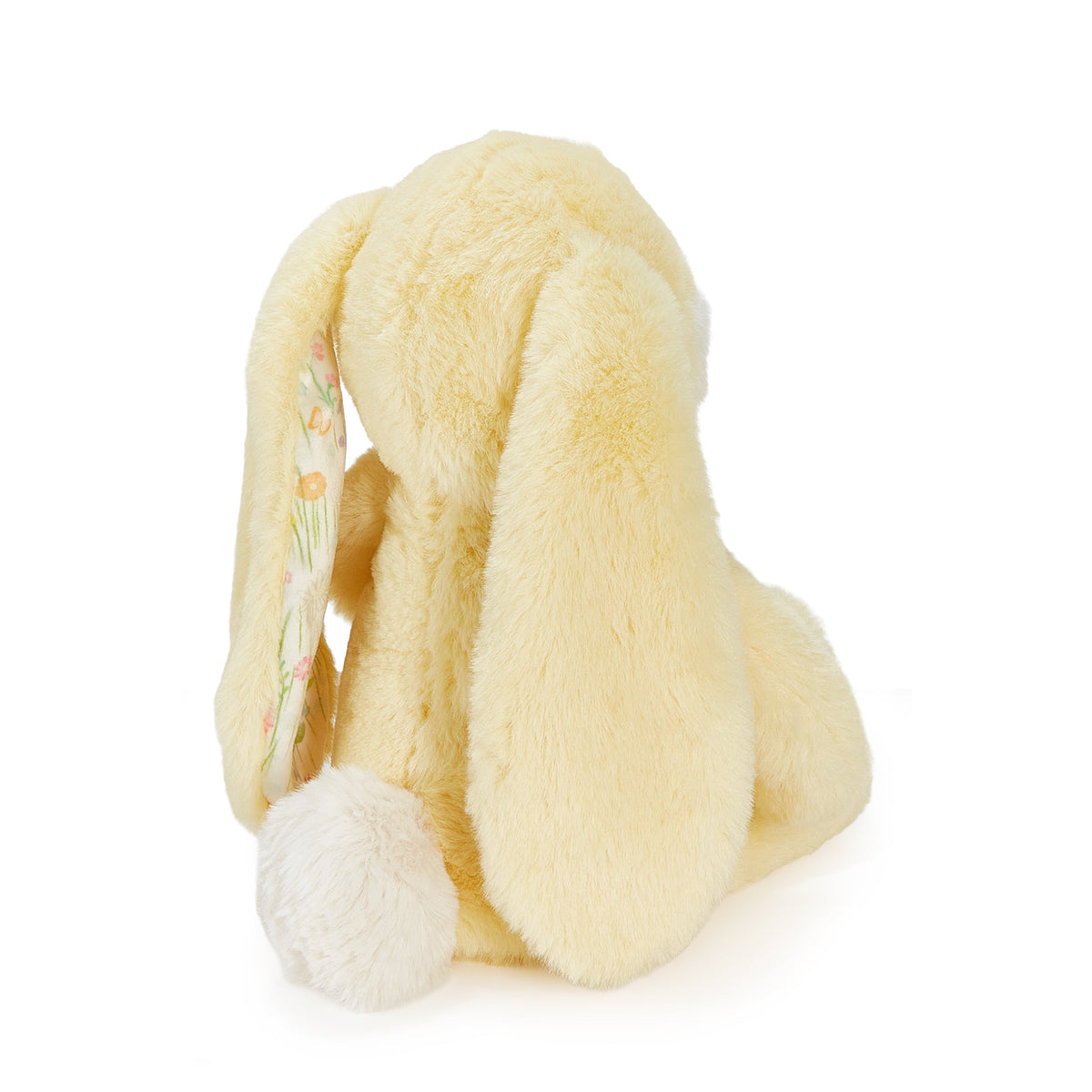 A pale yellow plush bunny toy shown from the back on a clean white background, with long floppy ears and a small floral pattern visible on one ear.