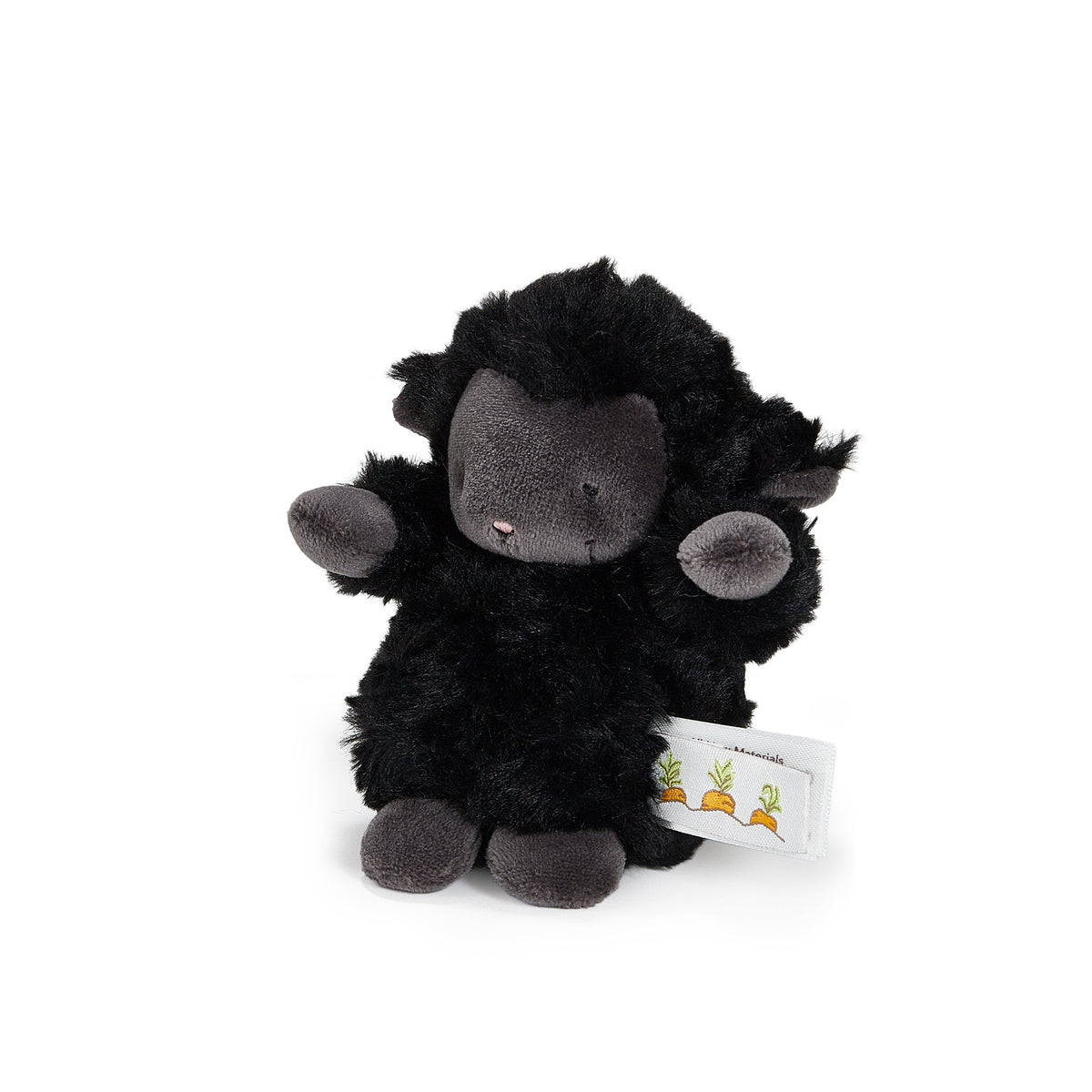 A small black plush sheep toy with a dark gray face, ears, and hooves, sitting on a white background. A small white fabric tag with a carrot illustration is attached to its side.